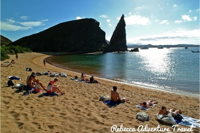 Bartolome beach with visitors sunbathing with the view of the Pinnacle Rock, Galapagos Islands 