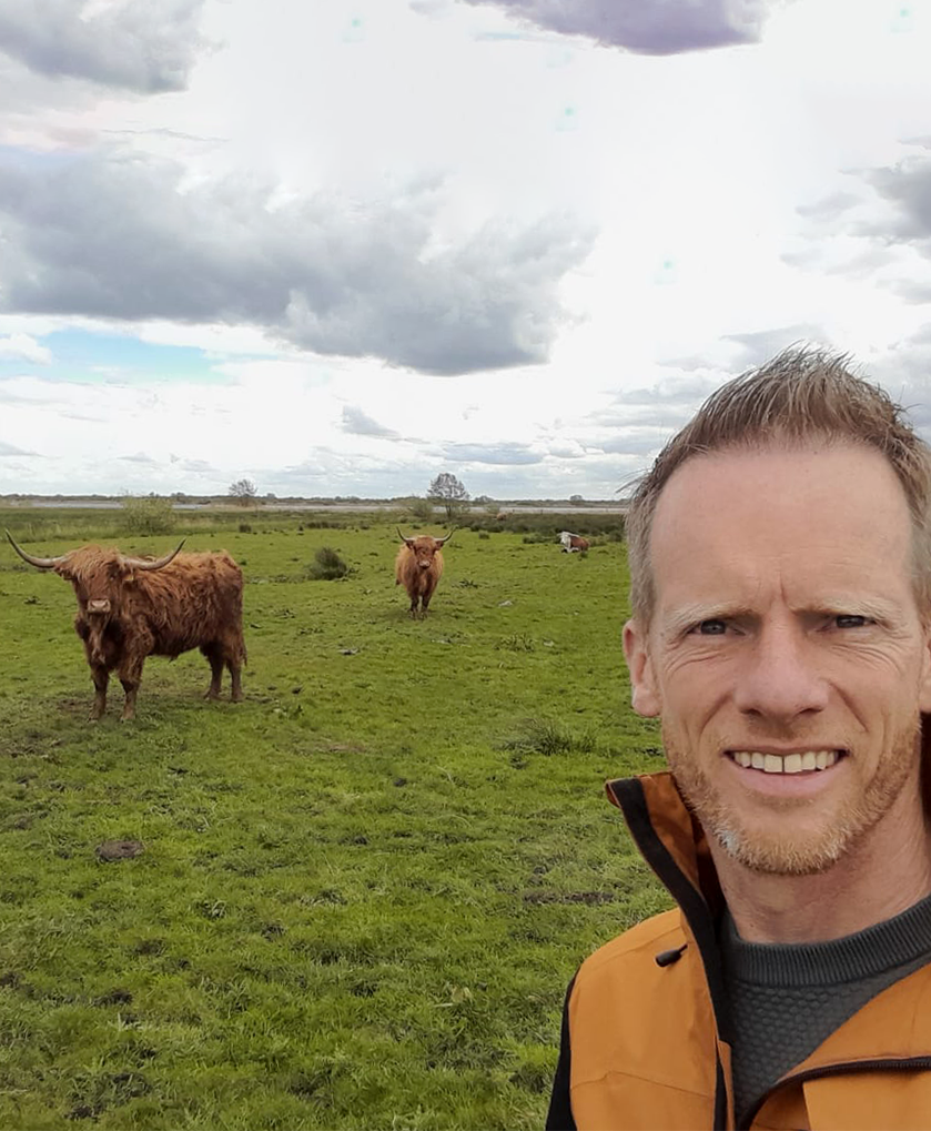 Boer Jelwin tussen kudde SchotseHooglanders en Herefords in natuurgebied.